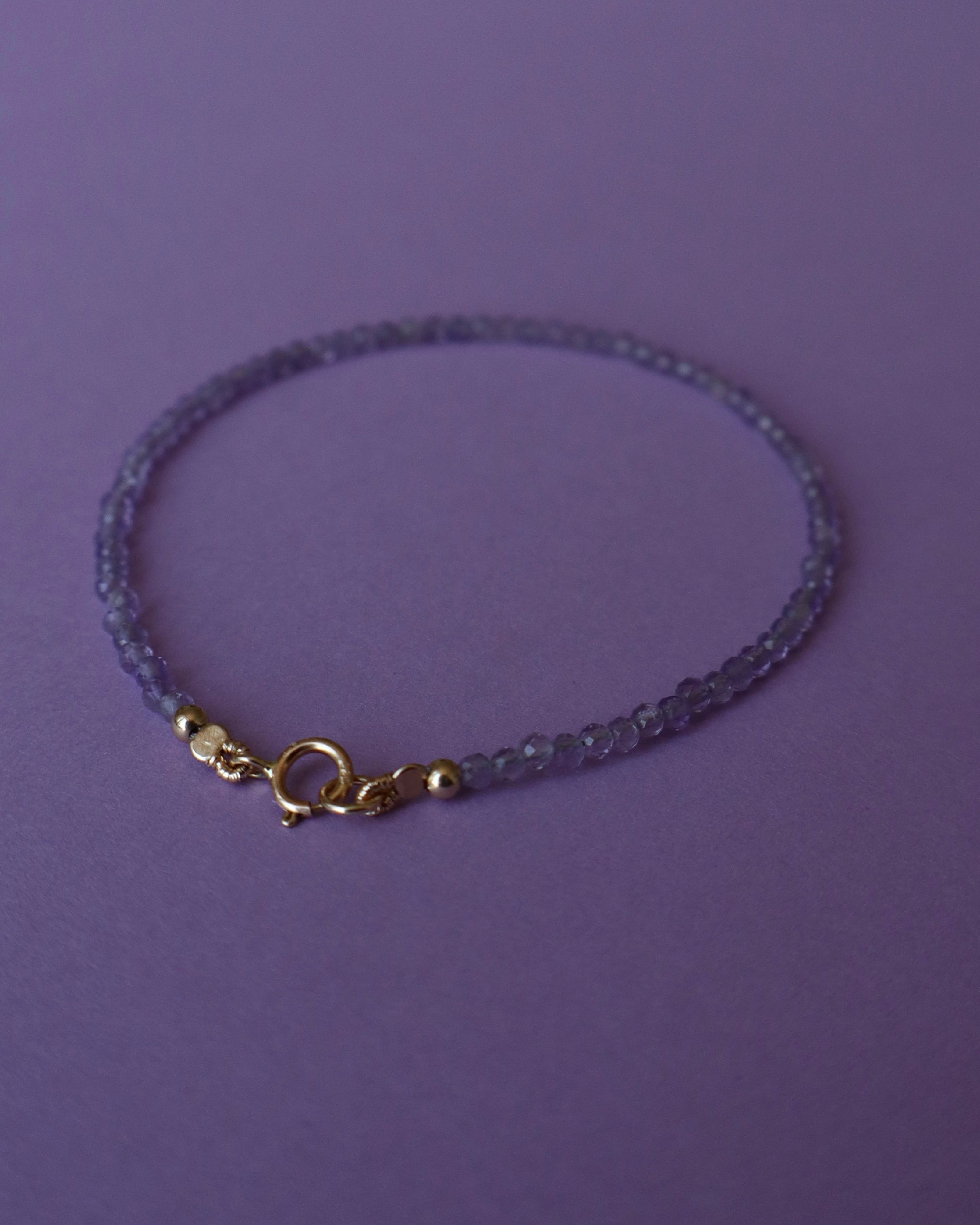 Delicate bracelet with a gold clasp on a purple background
