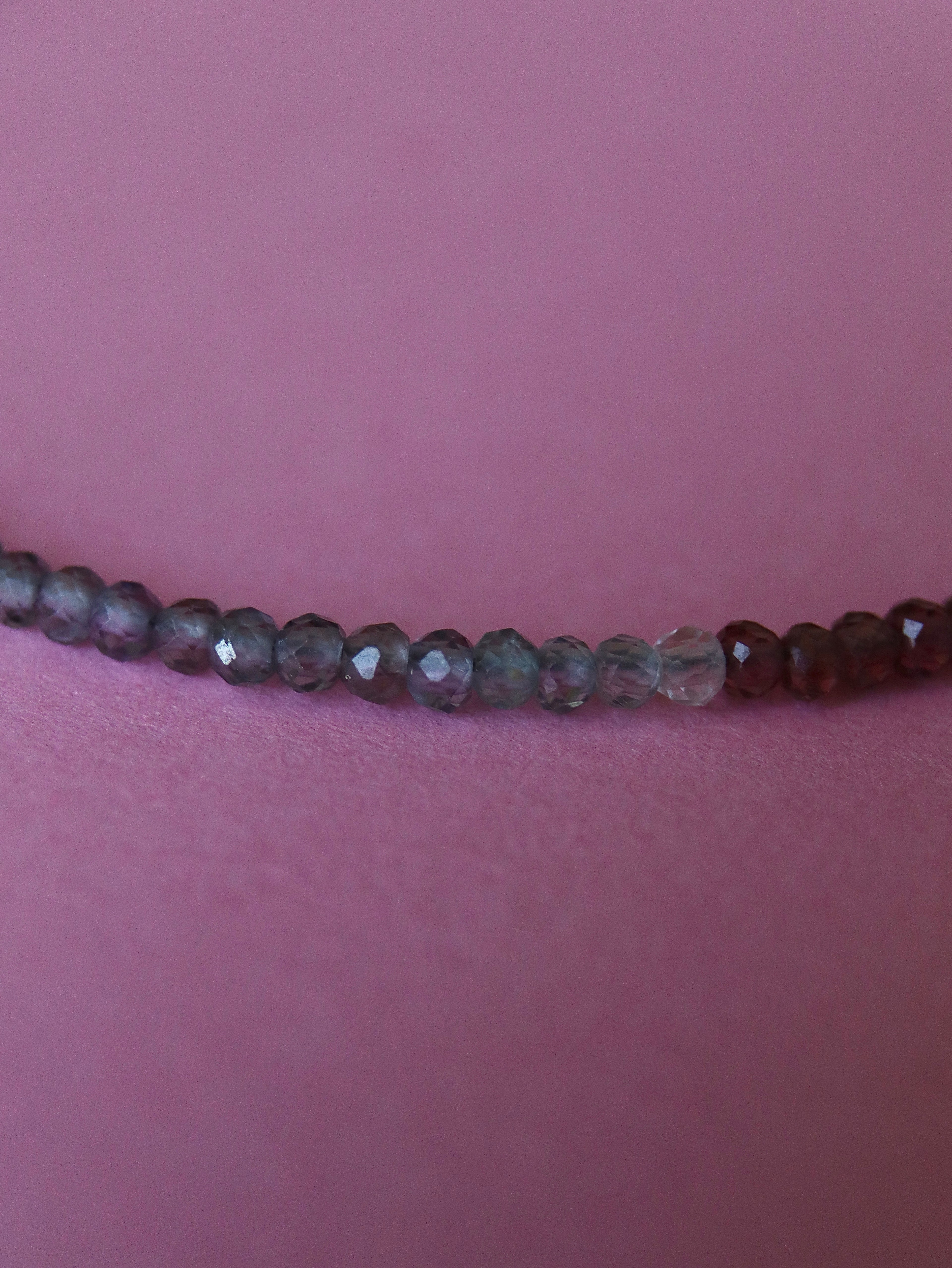 Close-up of a beaded bracelet on a person's wrist against a pink background