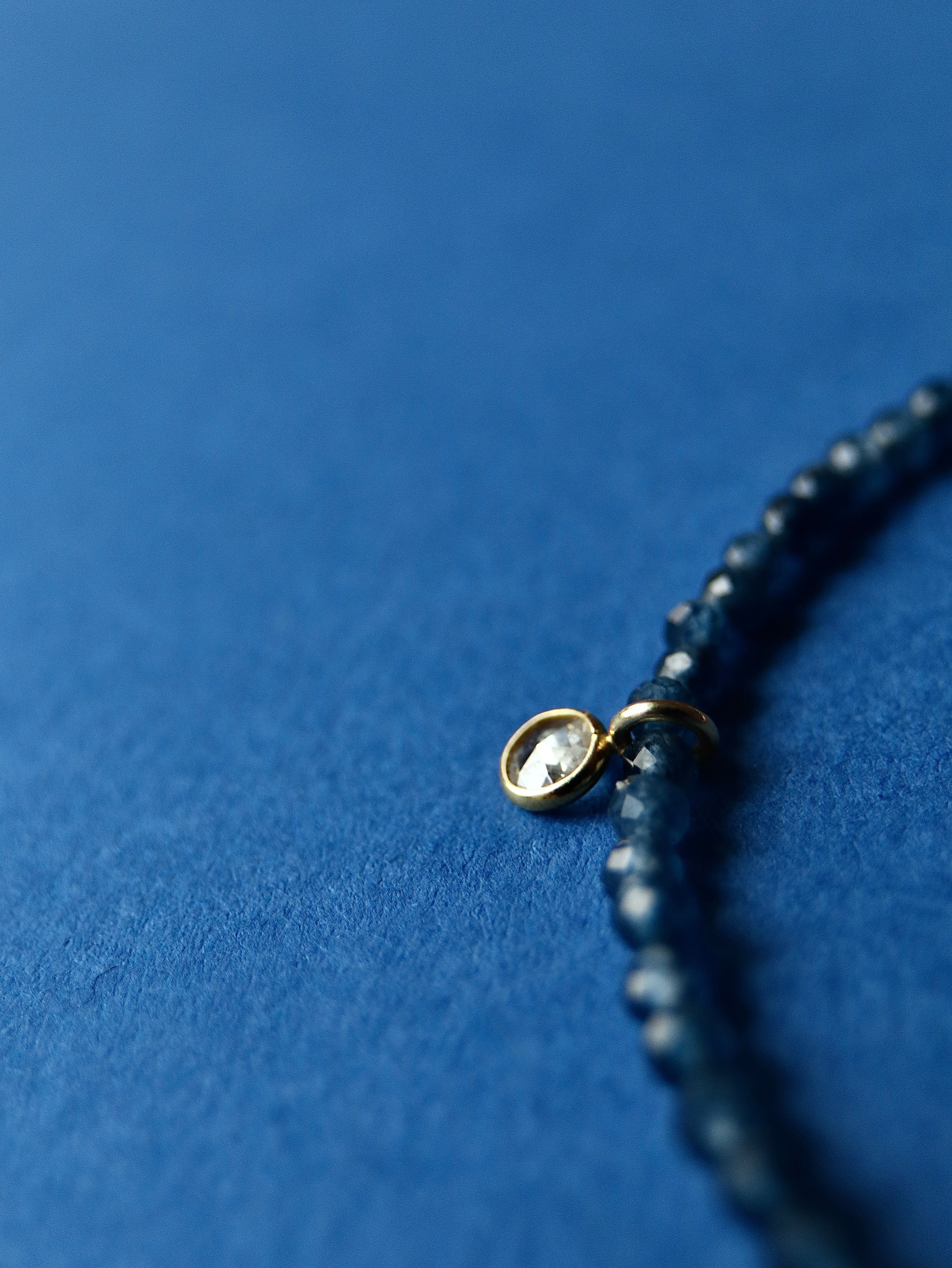 Close-up of a beaded bracelet with a gold clasp on a blue background