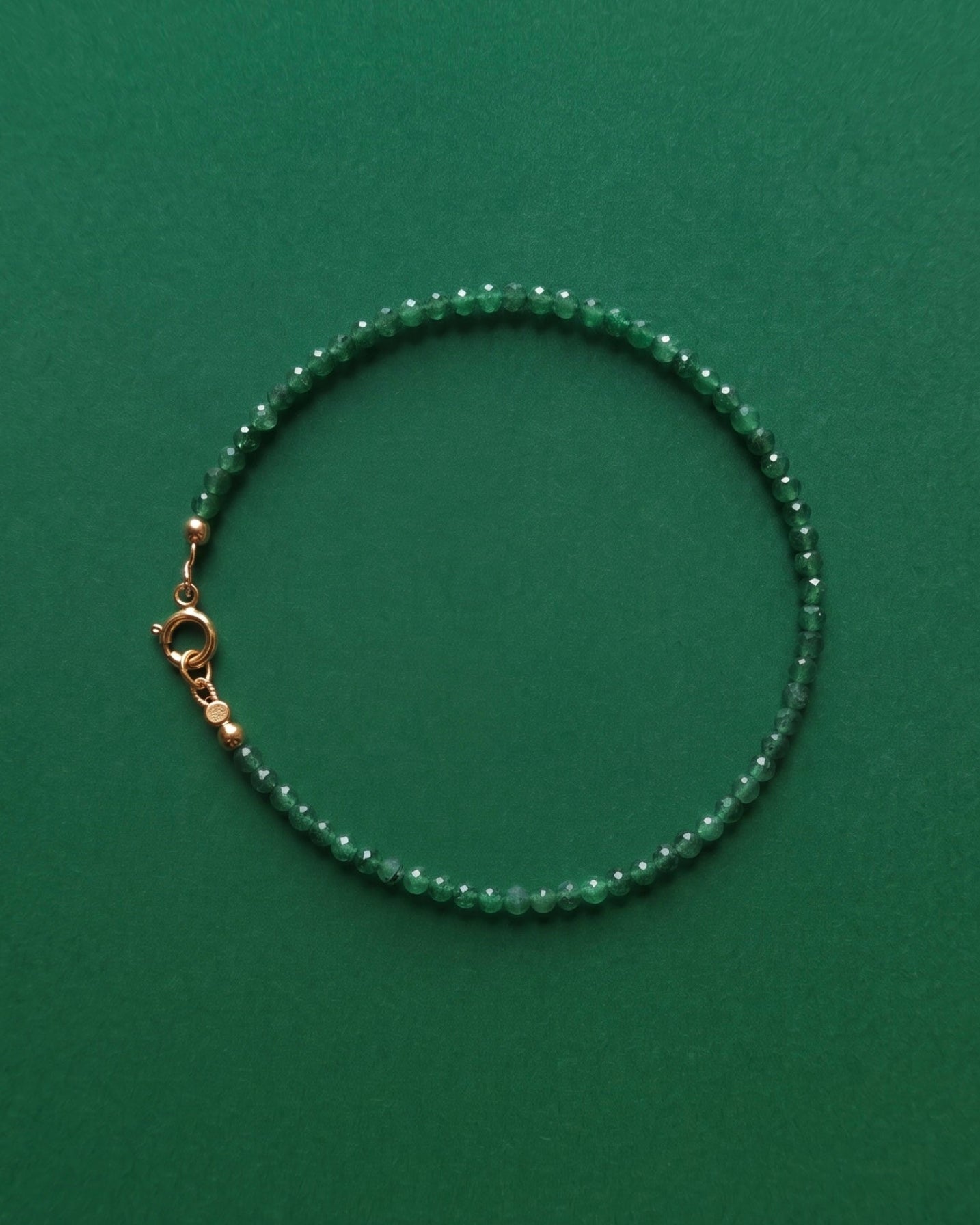 Green emerald beaded bracelet on a green background