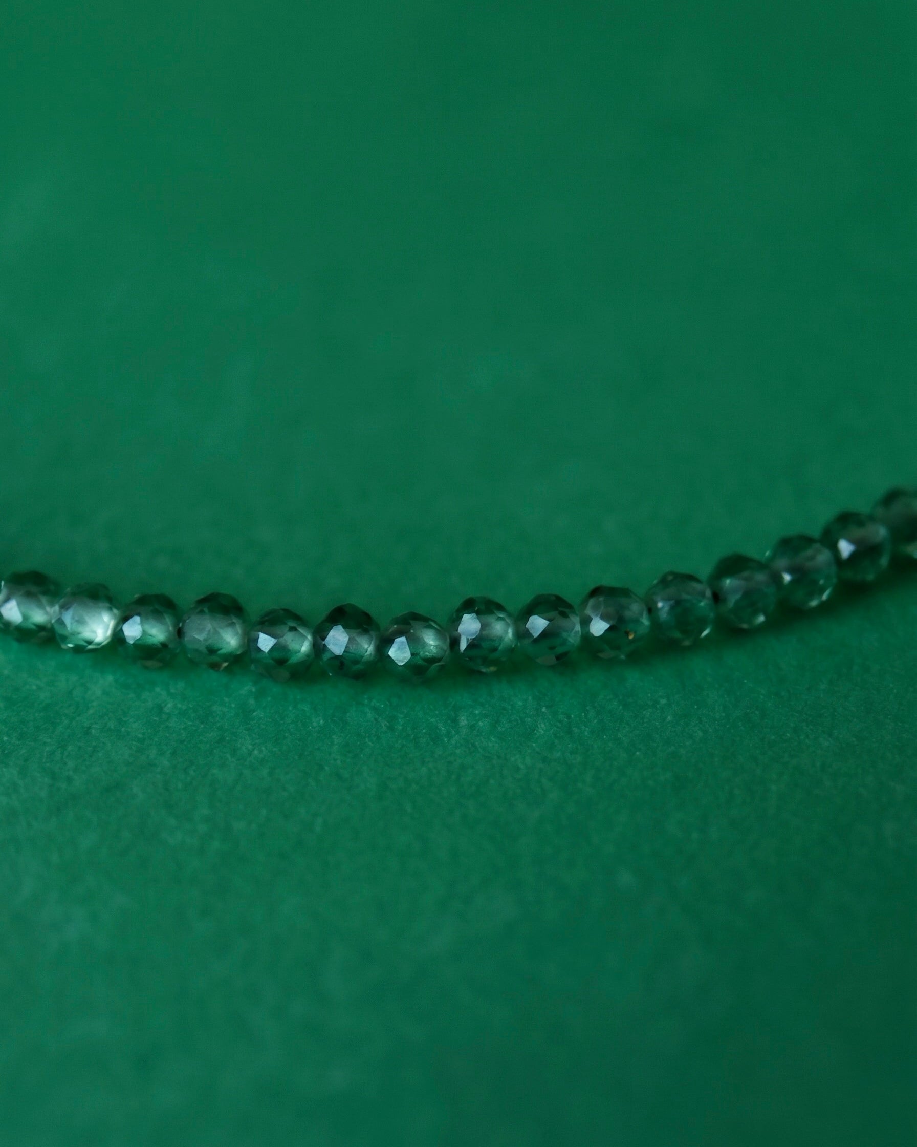 Green beaded necklace on a green background